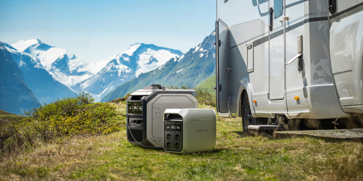 Zwei Solarspeicher von Ecoflow sind links seitlich von einem Wohnmobil im Bergpanorama platziert.